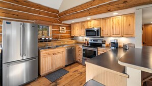 Une cuisine moderne avec des meubles en bois, des appareils en acier inoxydable et un plan de travail noir.