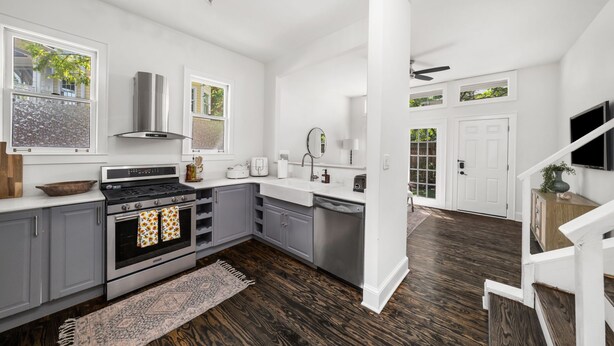 A modern kitchen with grey cabinets, a stainless steel stove, and a large window. - Walkable Grant Park 1920s home with King Bed (Atlanta)
