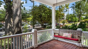 A covered porch with a wooden bench and white railings. - Walkable Grant Park 1920s home with King Bed (Atlanta)