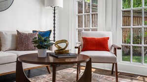 A living room with a sofa, armchair, round coffee table, and a potted plant. - Walkable Grant Park 1920s home with King Bed (Atlanta)