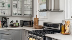 A modern kitchen with grey cabinets, a stainless steel stove, a microwave, and a coffee maker. - Walkable Grant Park 1920s home with King Bed (Atlanta)