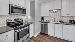 A modern kitchen with white cabinets, stainless steel appliances, and a geometric backsplash. - Modern 1-Bed, 1 Bath in the Heart of Breckenridge (Breckenridge)