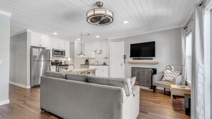 A modern living room with a grey sofa, wooden flooring, a kitchen with white cabinets, a flat-screen TV, and a fireplace. - Modern 1-Bed, 1 Bath in the Heart of Breckenridge (Breckenridge)