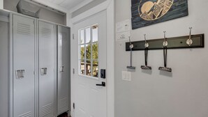 A hallway with lockers, a door with a window, a wall-mounted coat rack, and a framed artwork. - Modern 1-Bed, 1 Bath in the Heart of Breckenridge (Breckenridge)