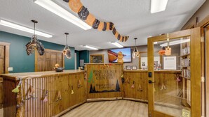 Un espace d’accueil avec un comptoir en bois, une enseigne indiquant « Centre d’accueil de Pine Ridge », et une vue sur un paysage montagneux par une fenêtre.