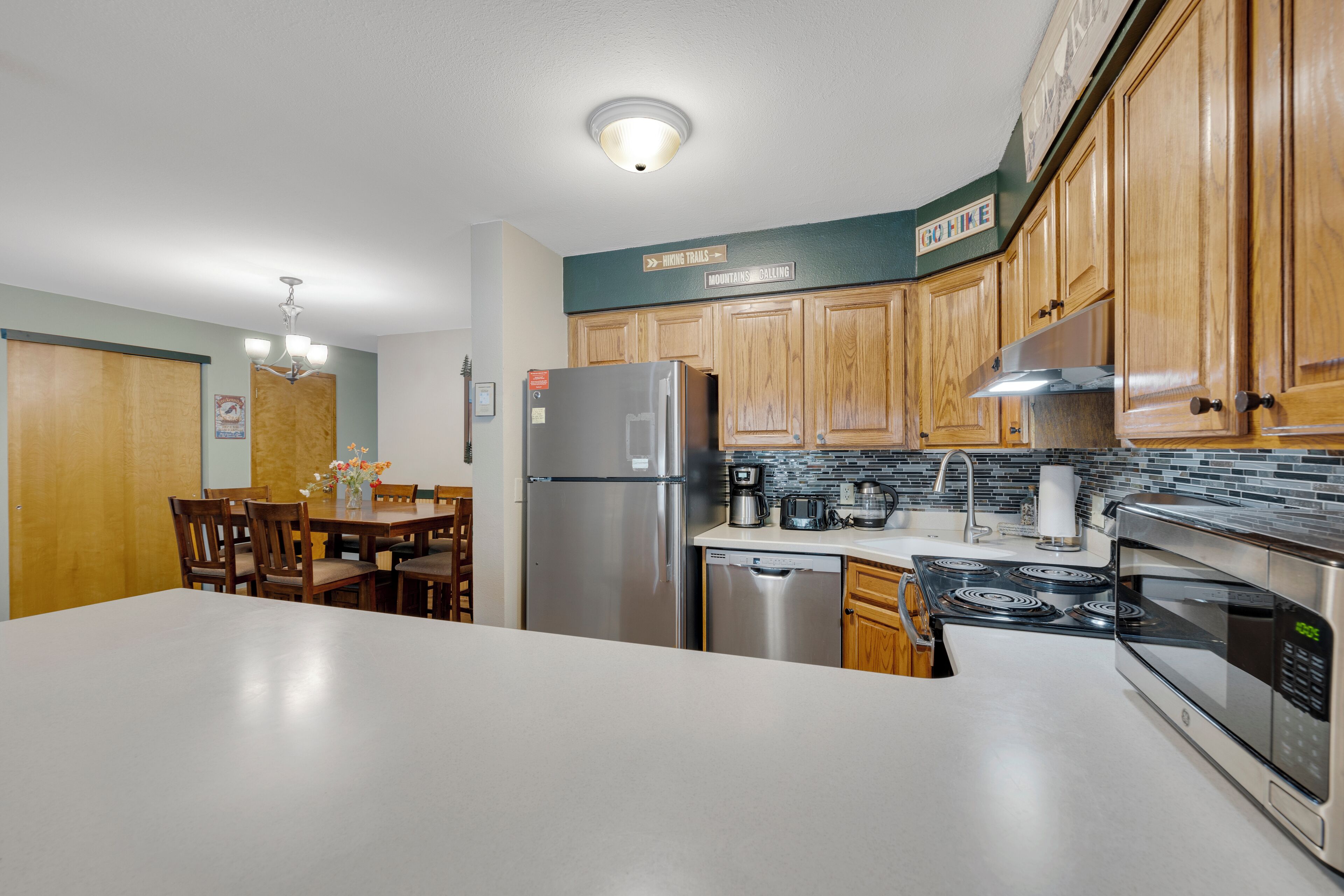 Una cocina moderna con armarios de madera, electrodomésticos de acero inoxidable y un comedor con mesa y sillas.