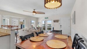 Un coin repas avec une table en bois, des sets de table en fibres tressées et des chaises noires.