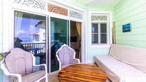 A balcony with a wooden table and two chairs, a sofa, and a sliding glass door leading to a kitchen. - Ocean Front, Direct Access to the Beach! (Sosúa)