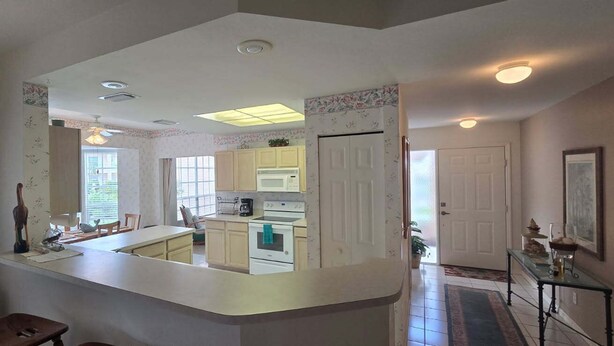 A kitchen with a central island, white cabinets, and a microwave. There is a dining area with a table and chairs.