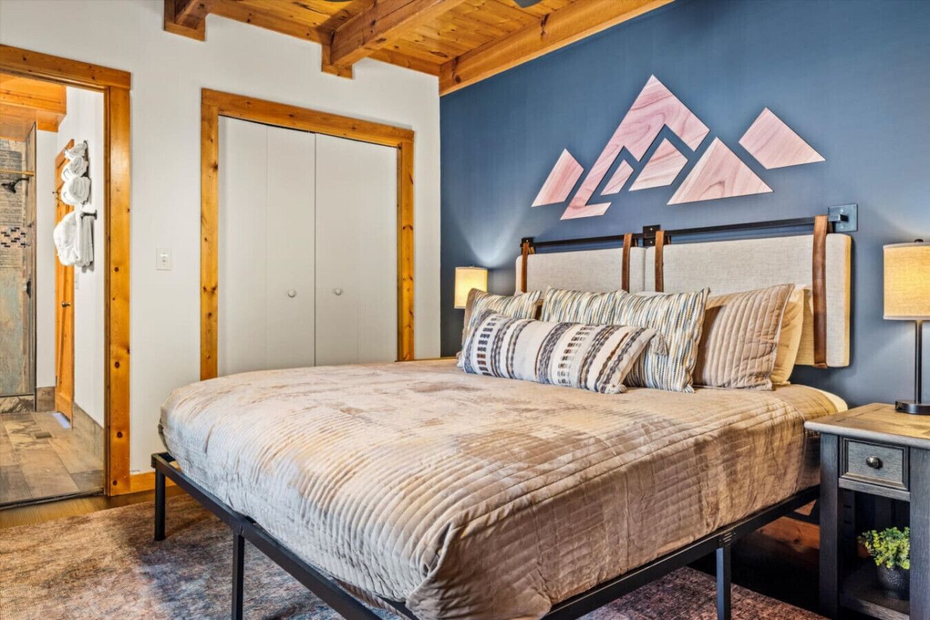 Een slaapkamer met een bed, nachtkastjes en een muur met geometrische patronen.
