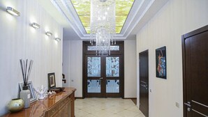 A hallway with a chandelier, a wooden cabinet, and a door with glass panels. - Villa Kali Nadyrova (Almaty)