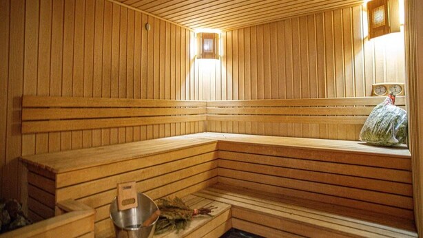 A wooden sauna with benches, a small window, and a heater. - Villa Kali Nadyrova (Almaty)