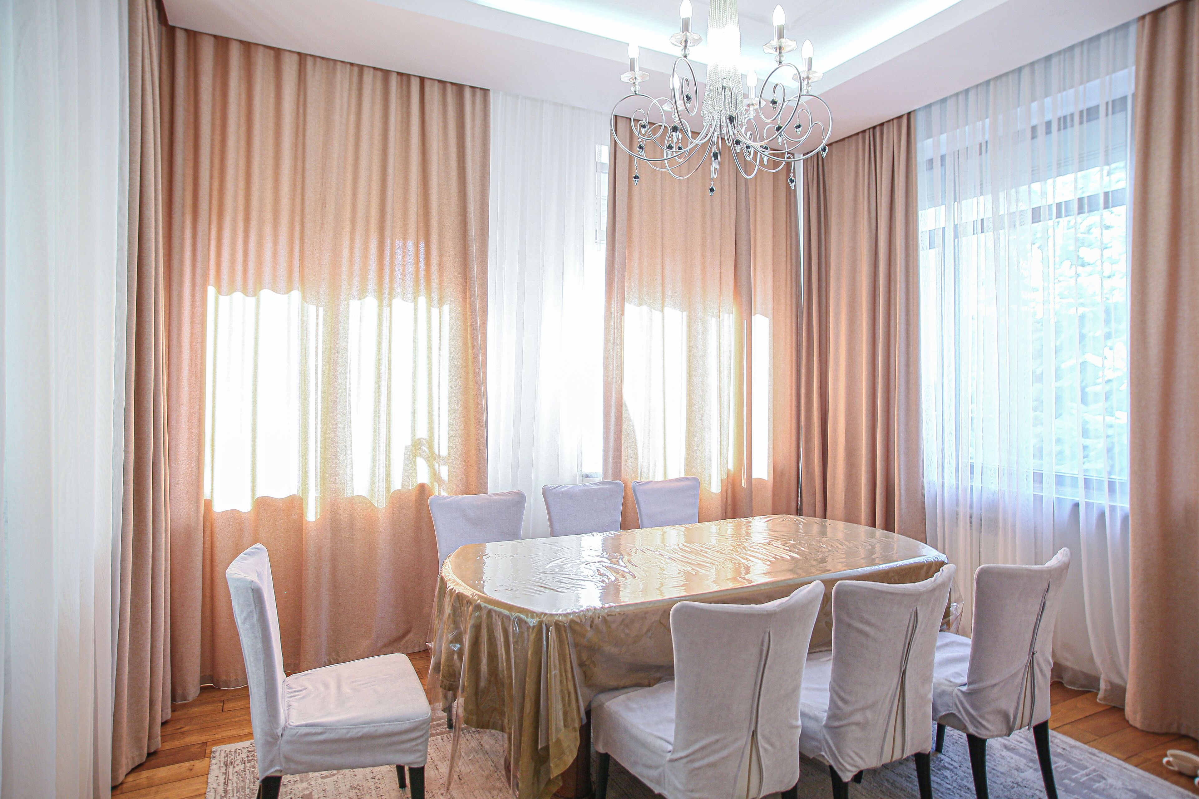 A dining room with a large oval table, six chairs, and a chandelier.
