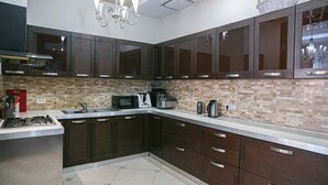 A modern kitchen with dark cabinets, a tiled backsplash, and stainless steel appliances. - Villa Kali Nadyrova (Almaty)