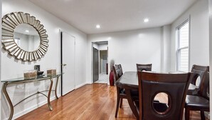 A dining area with a round mirror, wooden dining table, and chairs. - Cool- Private-Entire House-Near NYC-EWR/Free Parking-3beds/2bath (Bayonne)