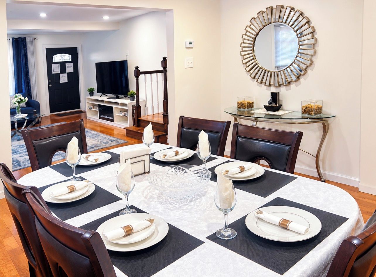 A dining area with a round table set for six, surrounded by chairs.