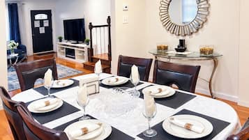 A dining area with a round table set for six, surrounded by chairs.