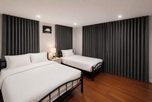 Une chambre d’hôtel avec deux lits, une table de chevet, une lampe et un tableau accroché au mur.