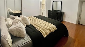 A bedroom with a bed, a dresser, a mirror, and a ceiling light fixture. - Cool- Private-Entire House-Near NYC-EWR/Free Parking-3beds/2bath (Bayonne)