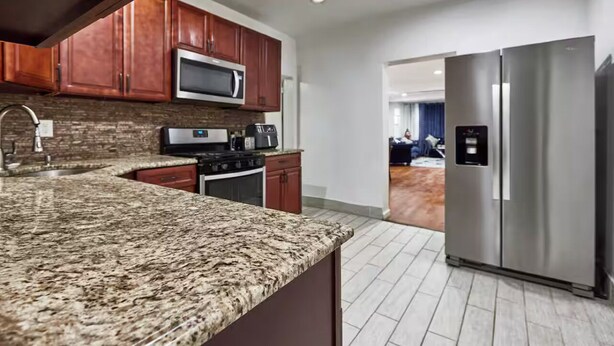 A modern kitchen with granite countertops, stainless steel appliances, and wooden cabinets. - Cool- Private-Entire House-Near NYC-EWR/Free Parking-3beds/2bath (Bayonne)