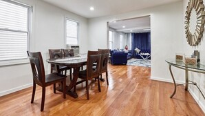 A spacious living room with a dining area, hardwood flooring, and a large window. - Cool- Private-Entire House-Near NYC-EWR/Free Parking-3beds/2bath (Bayonne)