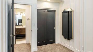 Une chambre à coucher comprenant un lit, une armoire, un miroir et une porte donnant sur une salle de bain.
