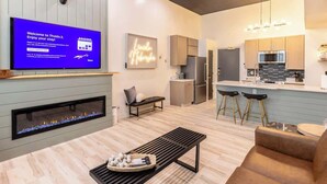 Une chambre d’hôtel moderne équipée d’une télévision à écran plat, d’une cheminée, d’un banc, d’un canapé, d’un coin cuisine et d’un bar.