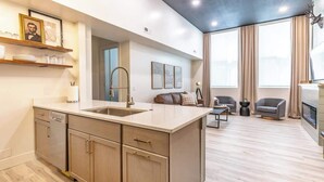 A modern kitchen with a central island, wooden cabinets, and a built-in dishwasher.