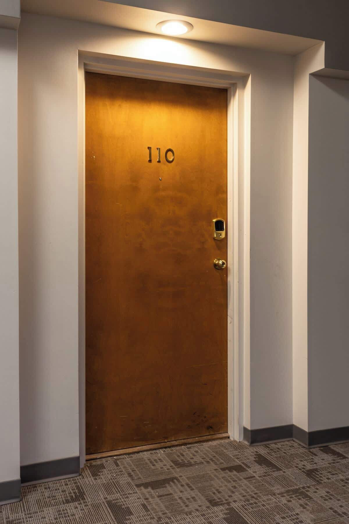 A wooden door with the number 110, a keyhole, and a small window.