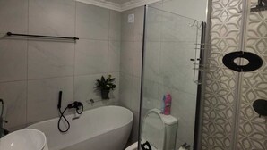 Un bagno moderno con una vasca da bagno indipendente, un WC e uno spazio doccia con pareti in vetro.