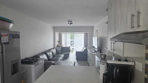 Una cucina moderna con isola centrale, elettrodomestici integrati e vista sull'area living.