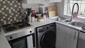 Una cucina funzionale con fornello, forno, lavatrice e lavandino.