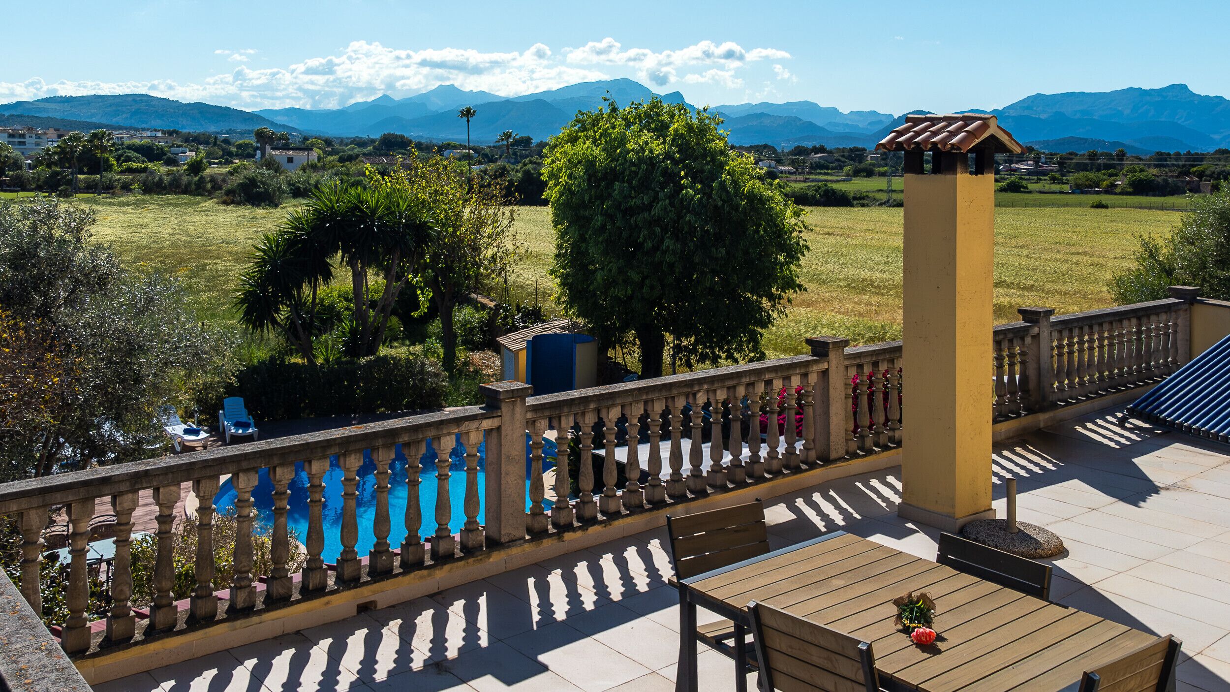 A terrace with a pool, outdoor seating, and a view of the mountains.