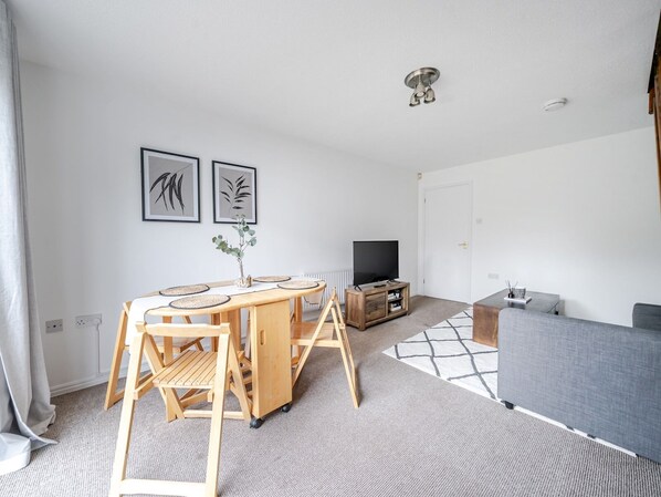 Un salon moderne avec une table à manger en bois, un canapé gris et un meuble pour la télévision.