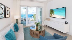 Un salon moderne avec un canapé, une table basse ronde et une vue sur l’océan par une porte-fenêtre coulissante.