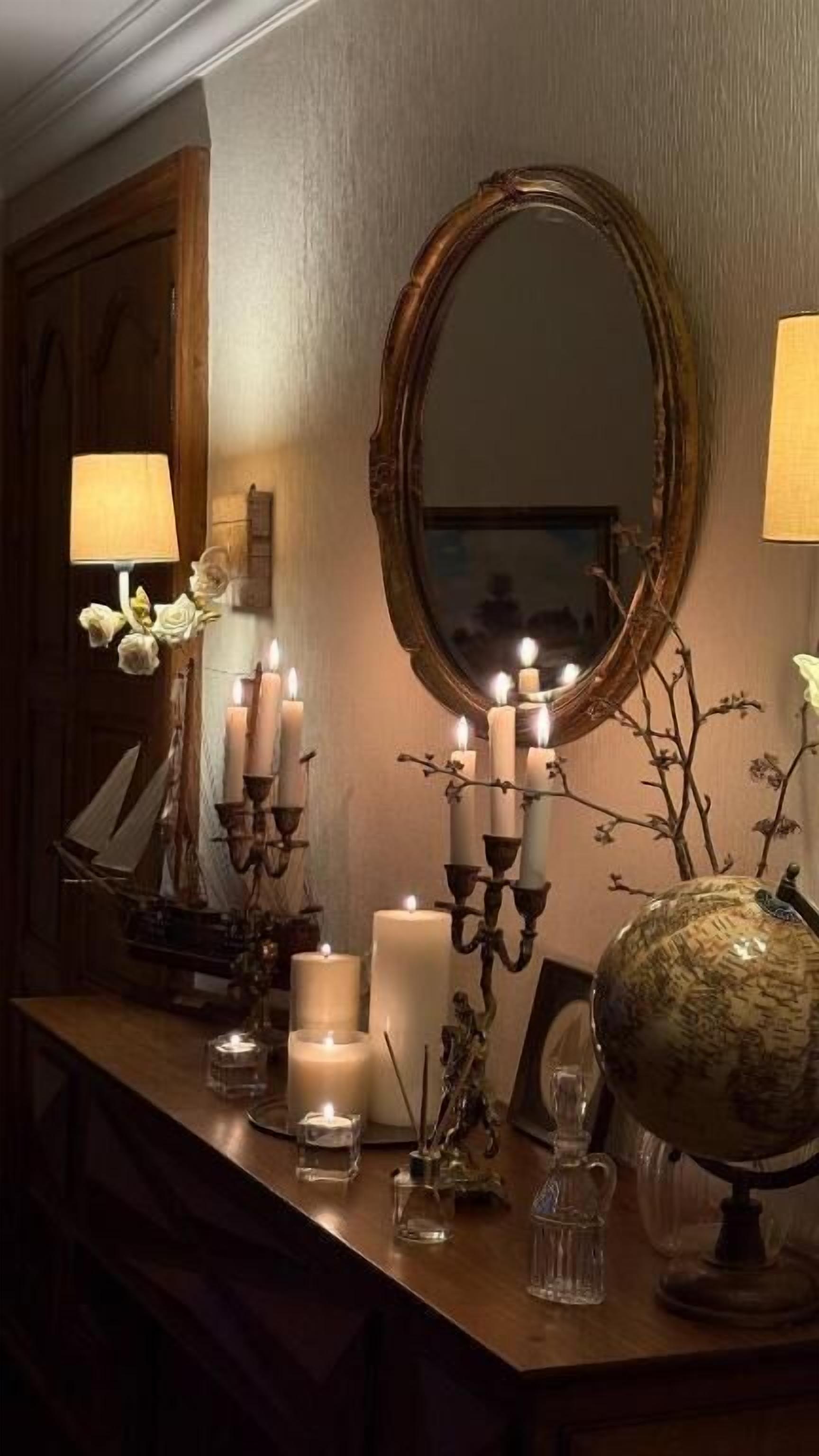 A room with a wooden vanity, a large mirror, and several lit candles.