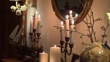 A room with a wooden vanity, a large mirror, and several lit candles.