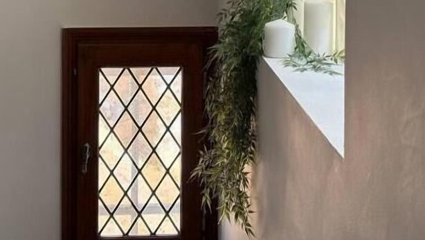 A room with a small window, a potted plant, and a white candle on the windowsill. - La Belle Vienne (Exideuil)