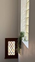 A room with a small window, a potted plant, and a white candle on the windowsill.