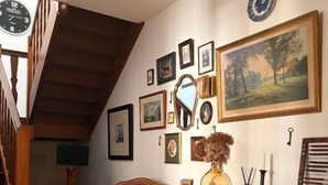A cozy room with a wooden staircase, a brown sofa, a desk with drawers, and various framed pictures on the wall. - La Belle Vienne (Exideuil)