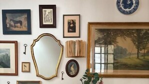 A room with a brown leather sofa, a white dresser with patterned tiles, and various framed artworks and decorative items on the walls. - La Belle Vienne (Exideuil)