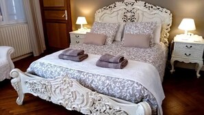 A bedroom with a large ornate bed, two bedside tables with lamps, and a wooden wardrobe. - La Belle Vienne (Exideuil)
