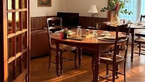 A dining area with a wooden table and chairs, a television, and a vase with flowers. - La Belle Vienne (Exideuil)