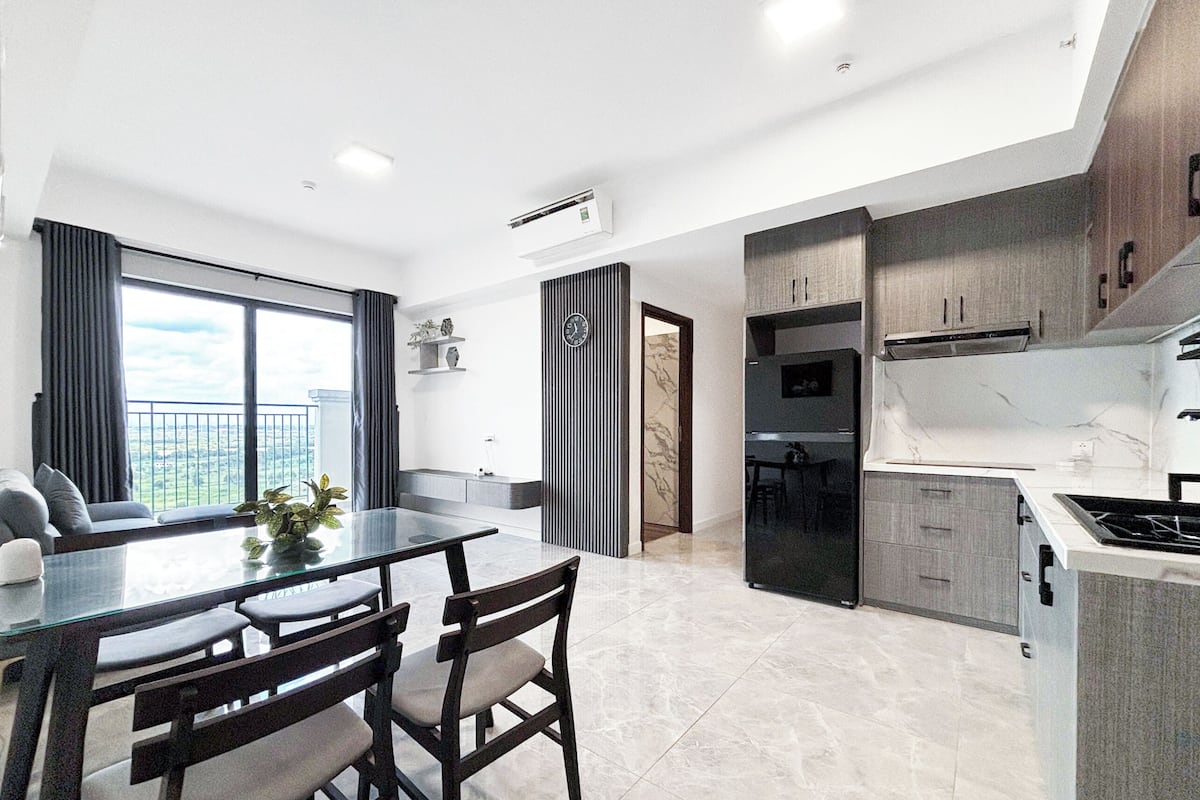 A modern kitchen with a dining area, large windows, and a view of the city.