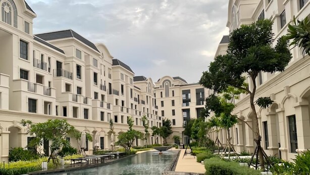 Un hotel con piscina central, rodeado de exuberante vegetación y arquitectura moderna.