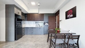 Una cocina moderna con armarios grises, encimera de mármol y comedor con mesa y sillas.