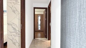 Un pasillo con paredes de mármol, puertas de madera y piso de baldosas.