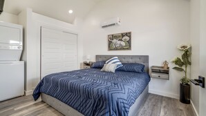 A bedroom with a bed, a nightstand, a dresser, an air conditioner, a painting, and a potted plant. - Charming 1-bedroom cottage on historic Rt. 66 on the west side of Yukon. (El Reno)
