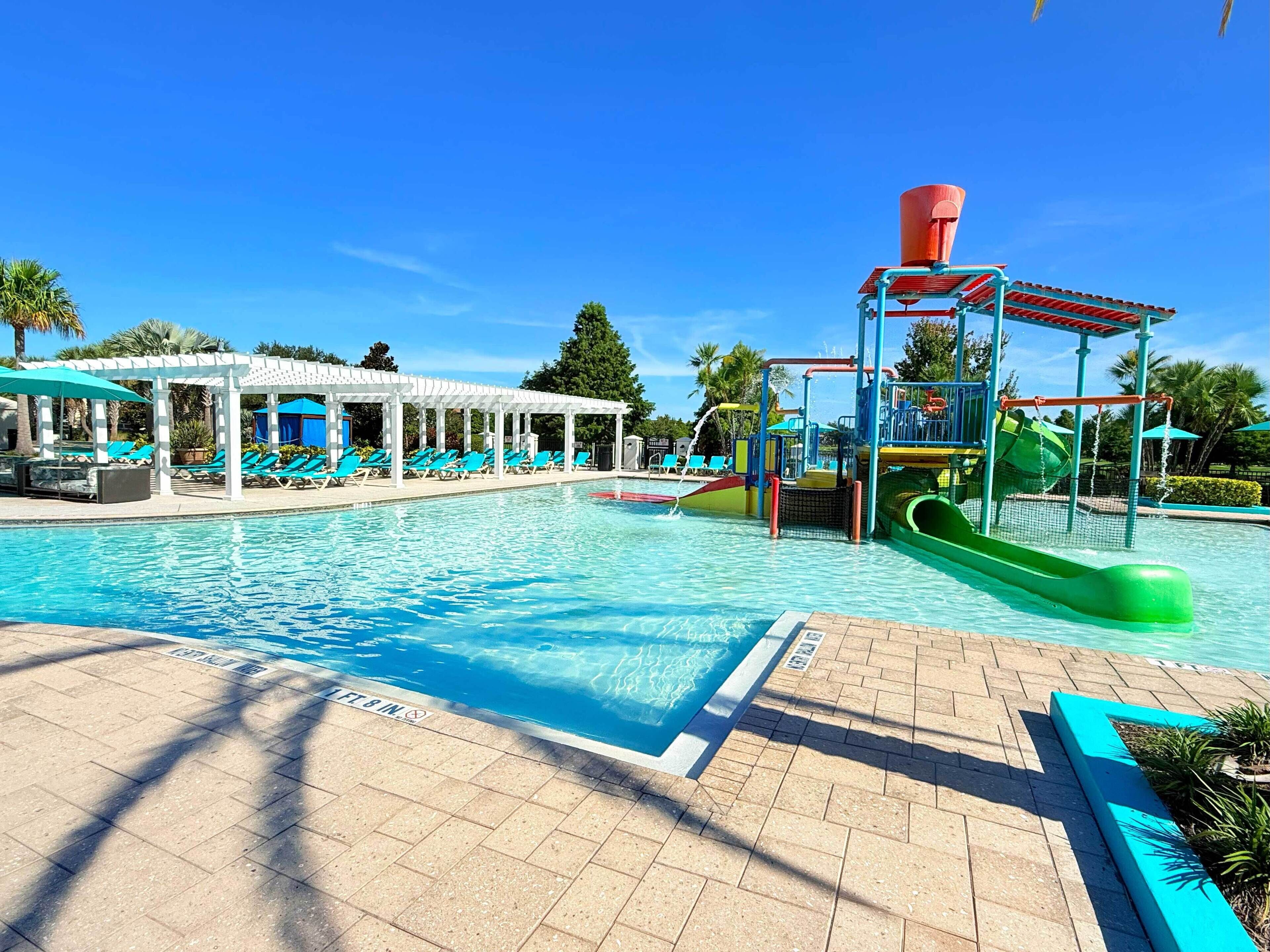 A swimming pool with a water slide and lounge chairs.