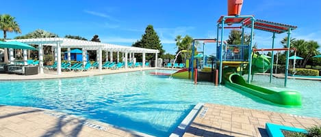 Una piscina con tobogán y sillas de descanso.